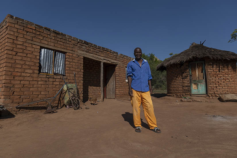 Hatred Chikwenga of Zibhowa village stands in front of his home which he plans to upgrade using income from selling eggs from his new poultry farm.