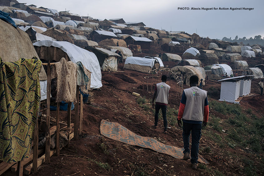 Photo of two men walking through a refugee camp in DRC