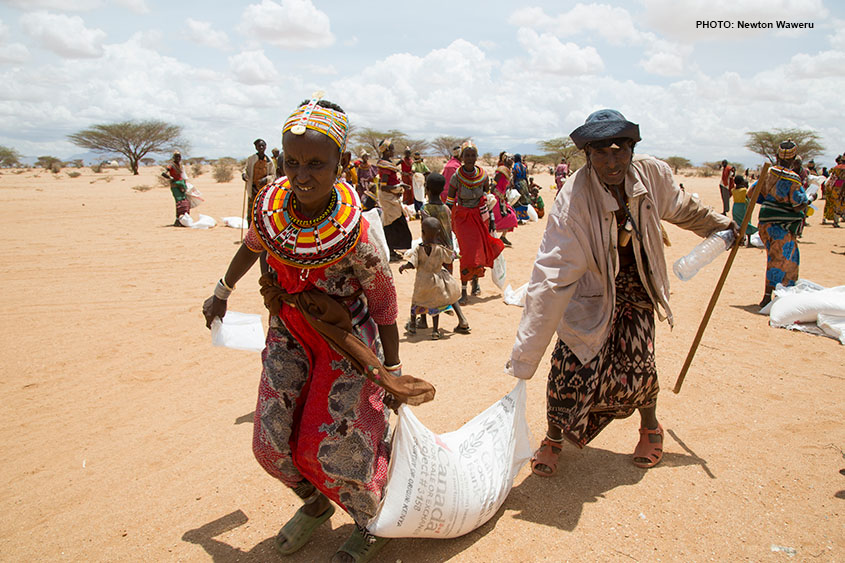 Two people carrying a bag of maize together