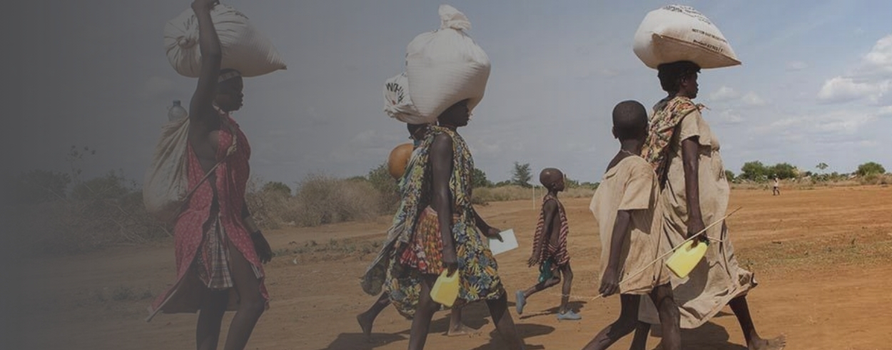 People walking carrying bags of grain.