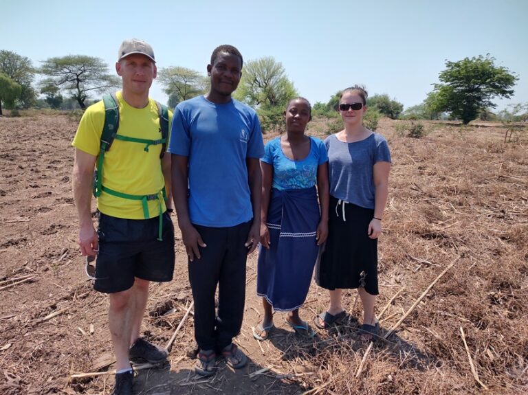 Four people standing in a field in Malawi.