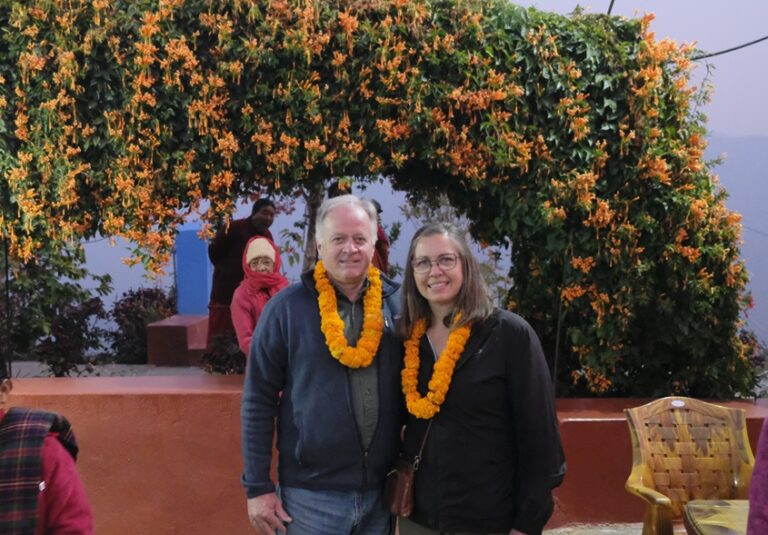 Two people standing in front of a flower arch.