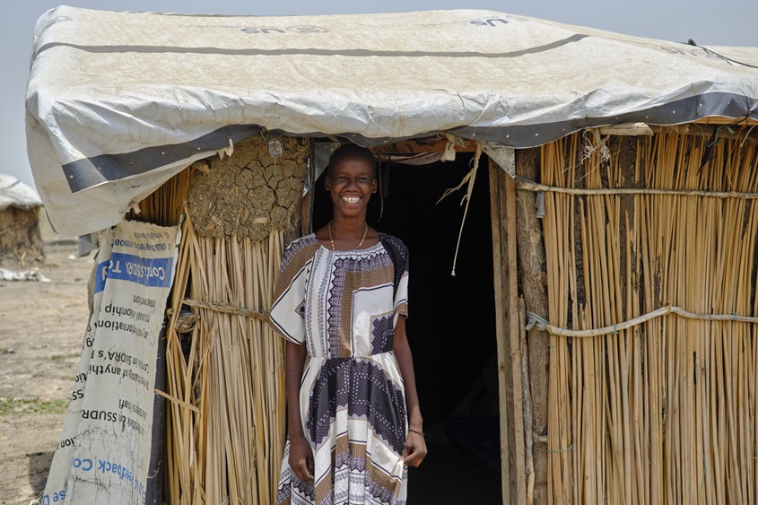 A woman standing in front of her home in South Sudan.